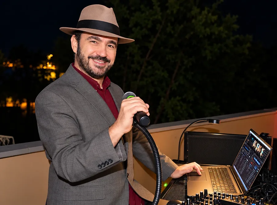 DJ Tibor at his booth with a microphone during an evening event