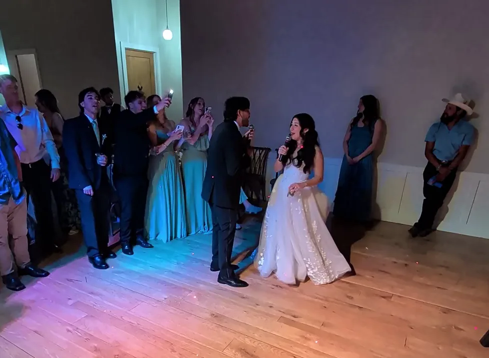Bride and groom singing karaoke together at their wedding reception