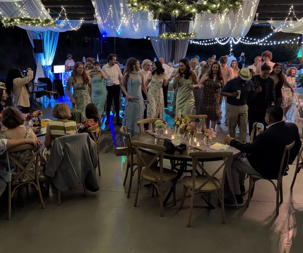 Guests filling the dance floor at a wedding reception under string lights
